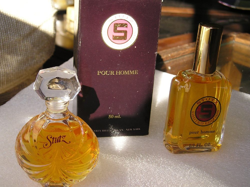 Stutz Pour Homme cologne — crystal flacon and gold-capped travel bottle with the Stutz roundel, beside the maroon 50 ml presentation box